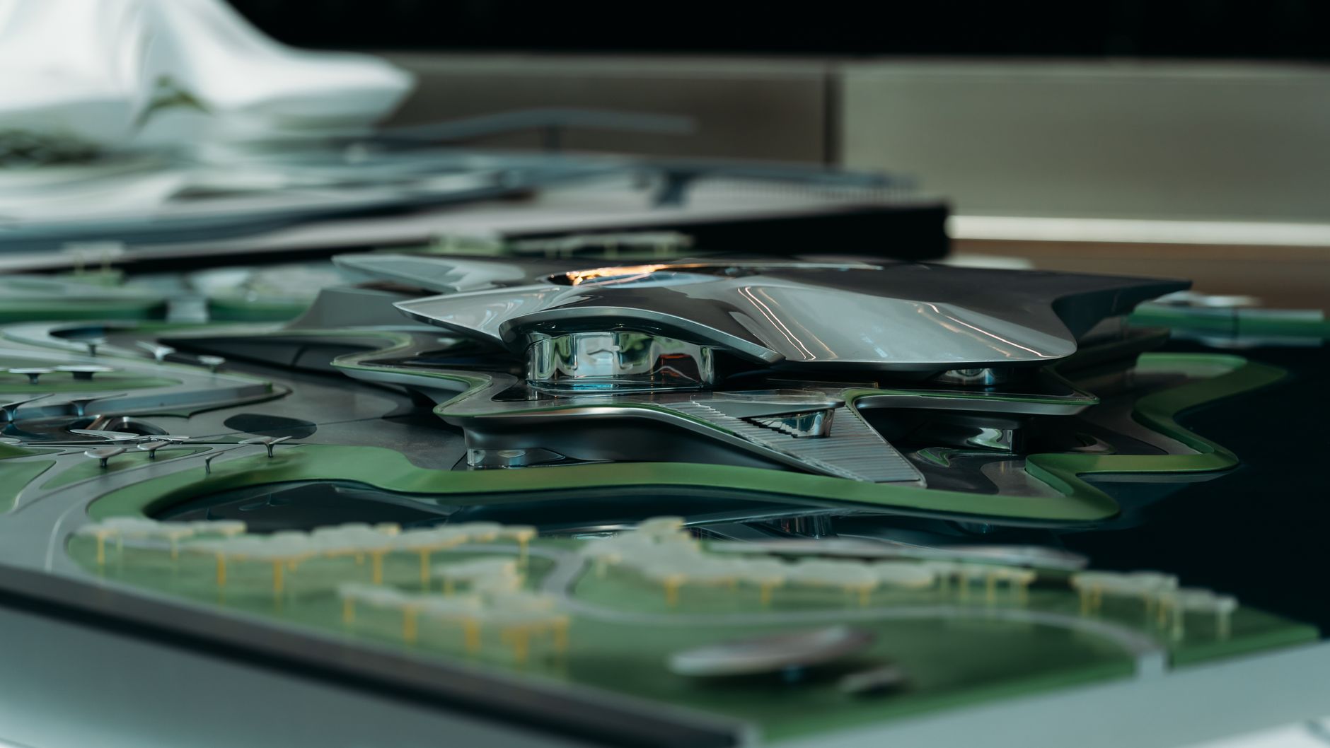 Modelo arquitetônico futurista de estrutura metálica inserida em uma área verde.