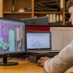 Engenheiro trabalha com software CAD em dois monitores em um escritório.