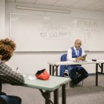 Fiscal acompanha estudantes durante a realização de uma prova em uma sala de aula.